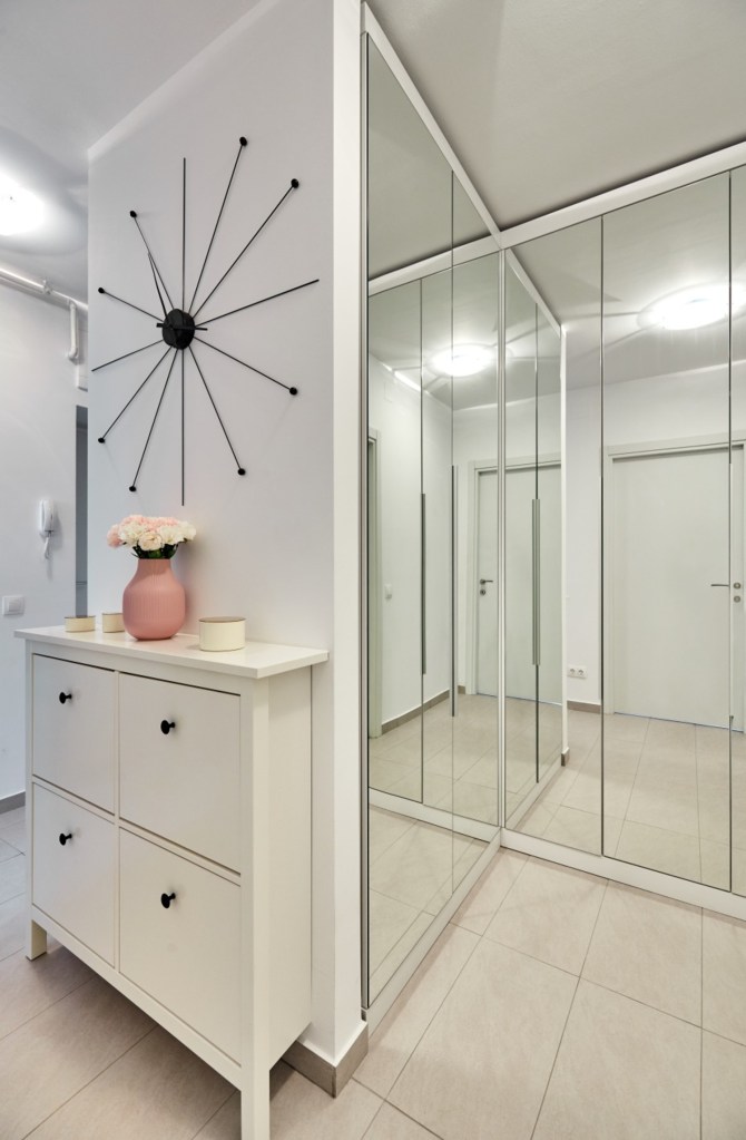 Dulap în formă de L placat cu oglinzi. Amenajare apartament două camere București, arh. int. Cristina Micu.