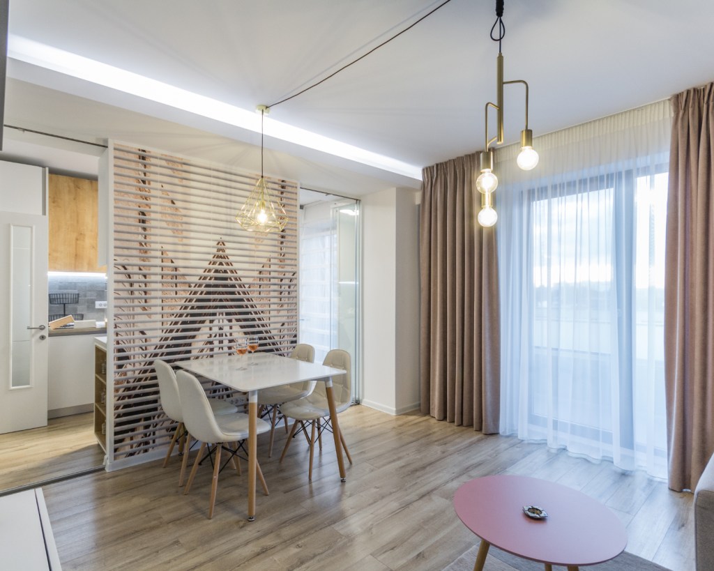 amenajare open space cu bucătărie separată de living prin geam. Zonă de dining. Stil scandinav
