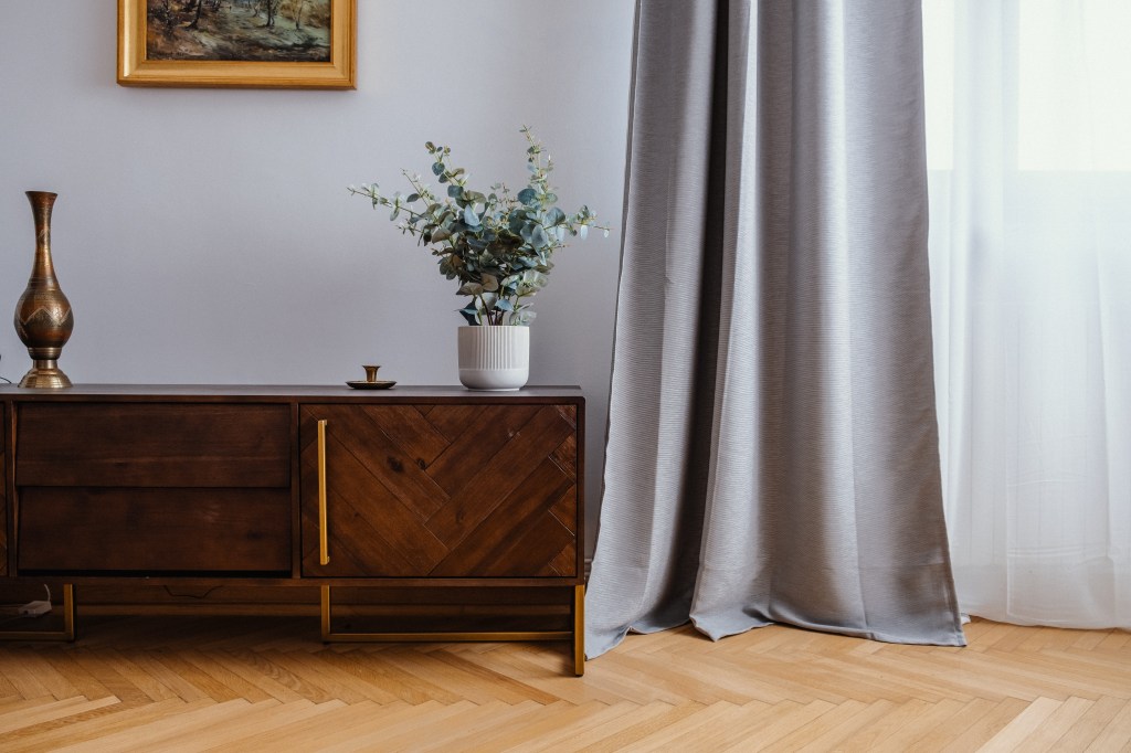 living cu draperii gri comoda in stil mid century modern si parchet din lemn chevron