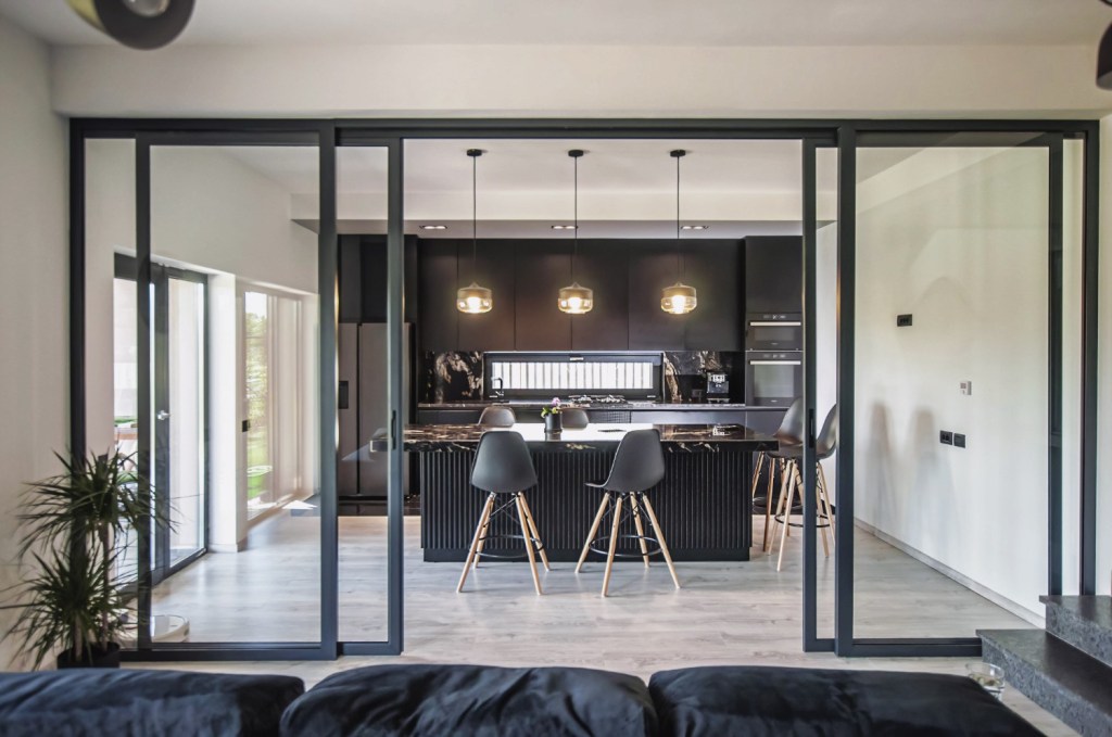 închidere bucătărie open space glasvand culoarea negru Amenajare casă Iași - decor negru modern - living separat de bucătărie cu uși de sticlă cu cadru metalic