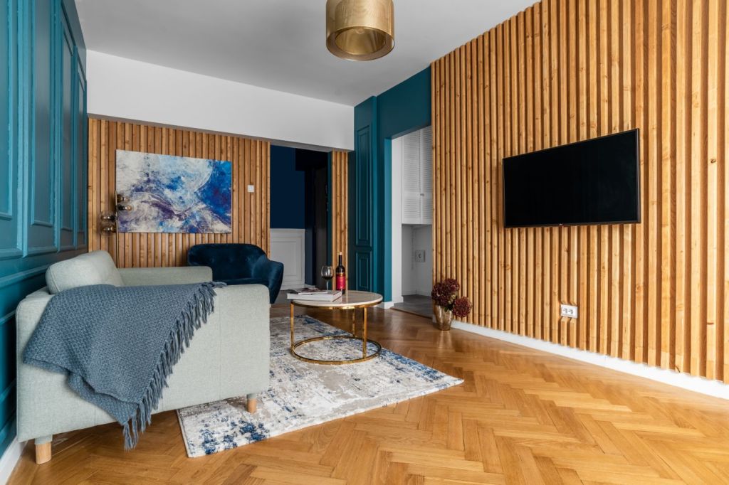 living perete riflaj lemn vopsea albastra lambriuri parchet lemn natur model chevron corp de iluminat auriu