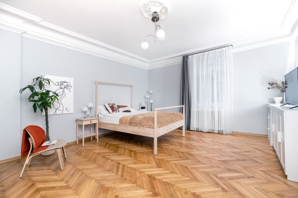 Dormitorul e amenajat minimalist, cu un pat cu baldachin IKEA și o comodă albă.