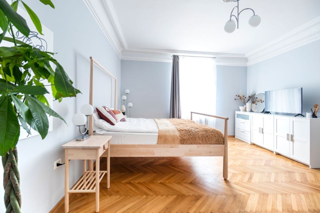 Dormitorul e amenajat minimalist, cu un pat cu baldachin IKEA și o comodă albă.