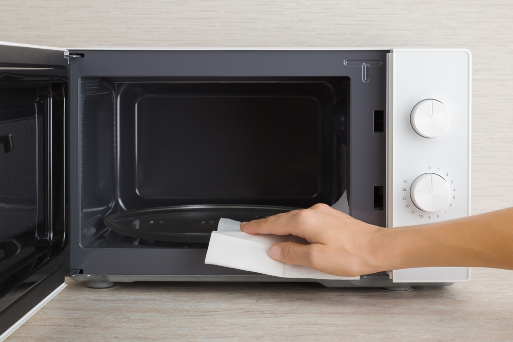 femeie curata cu un servetel cuptorul cu microunde