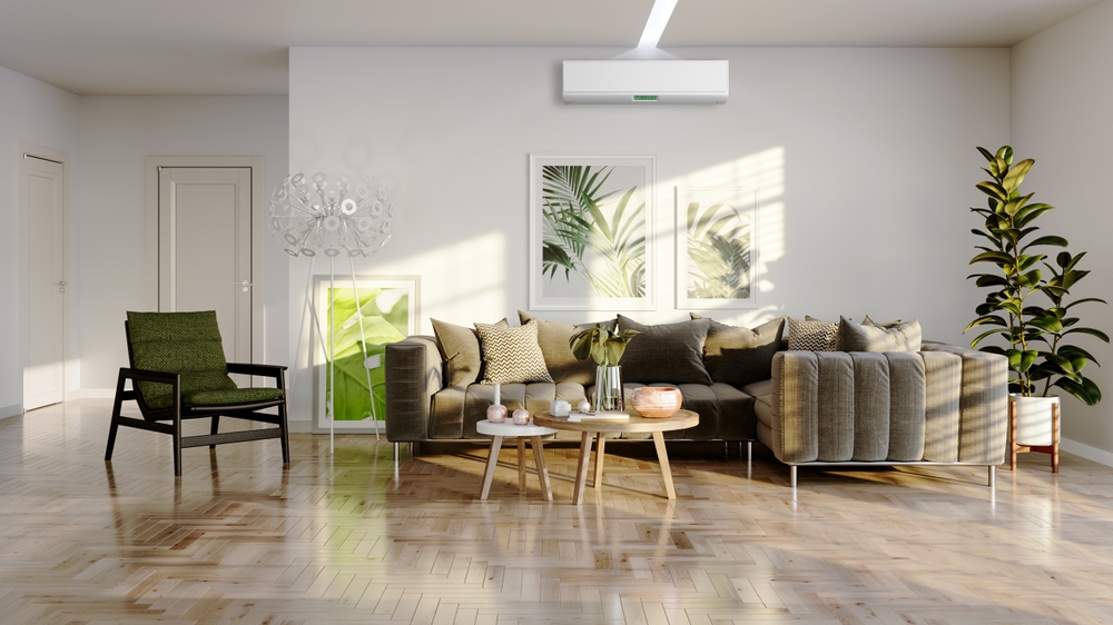 Mascare aer condiționat: Un living luminos, amenajat în stil modern. Pe perete se reflectă razele soarelui, peste tablouri și unitatea de aer condiționat.