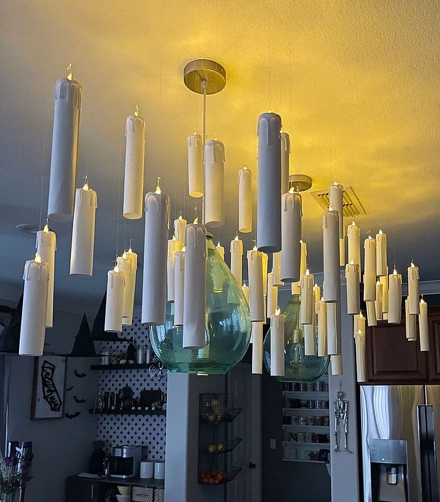 Lumânări albe plutitoare agățate de tavan cu gută transparentă, ca decor de Halloween.