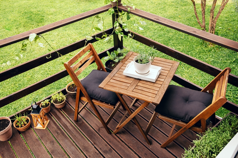 mobilier de gradina din lemn pe deck de lemn la casa cu curte verde