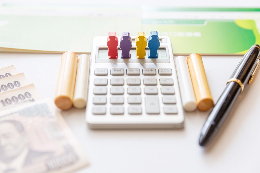 succesiune reprezentare cu figurine colorate din lemn pe masa cu calculator pix si bani