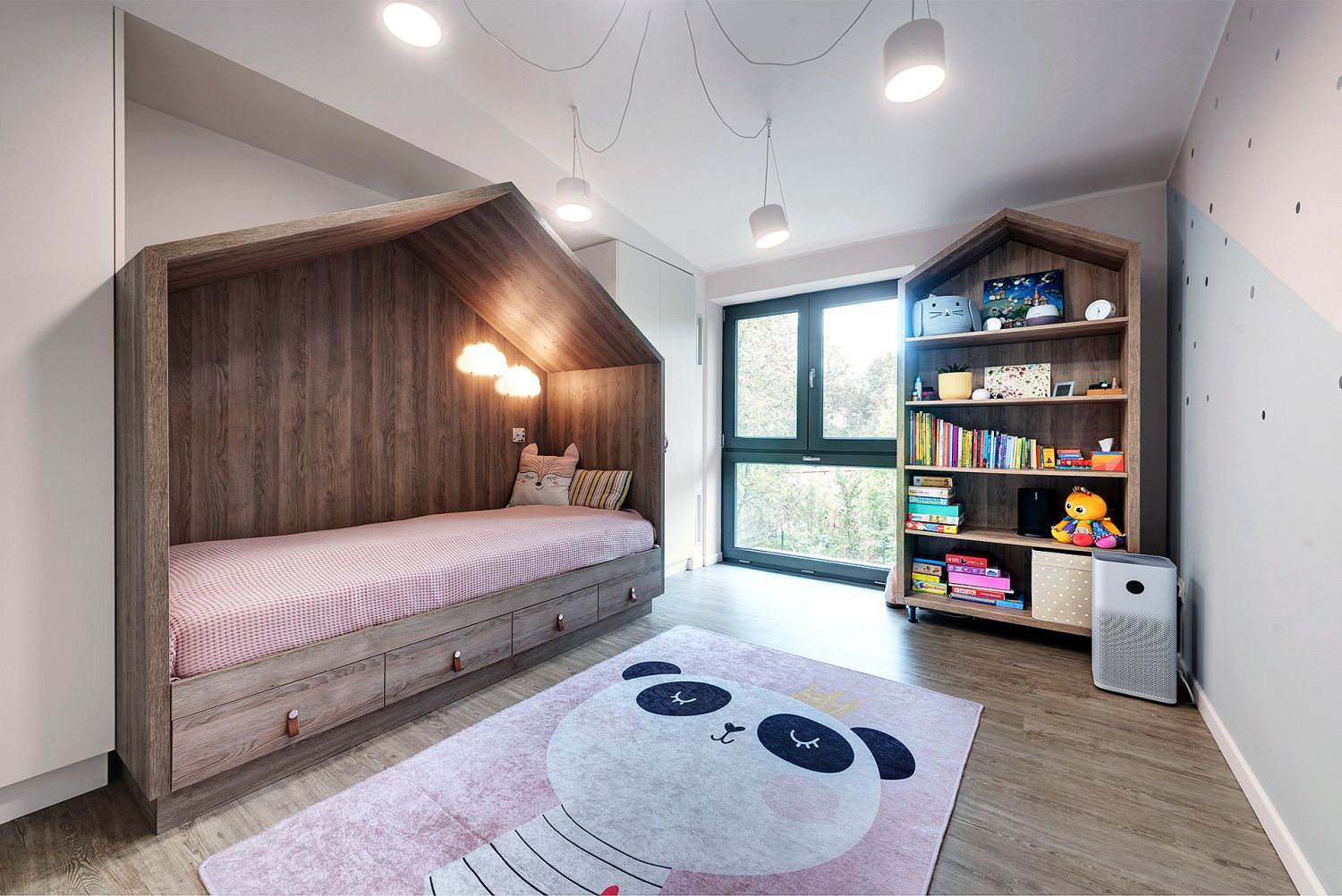 amenajare camera copii cu pat casuta covor cu panda roz si biblioteca tot in forma de casuta