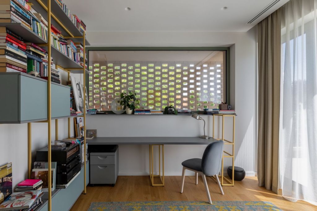 birou amenajat intr-o casa cu etaj din corbeanca, cu parchet din lemn si mobilier gri deschis, biblioteca pentru carti si decorațiuni