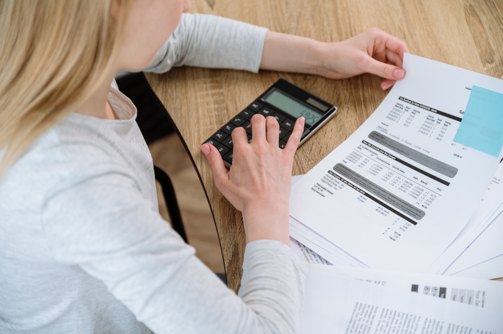 calcule făcute de femeie tânără cu calculator si foi pentru neplata întreținere bloc