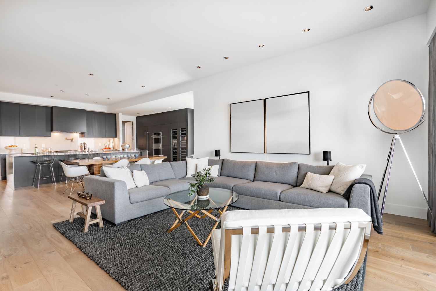 canapea sau coltar intr-un living open space cu bucatarie stil modern covor gri inchis fotoliu pereti albi