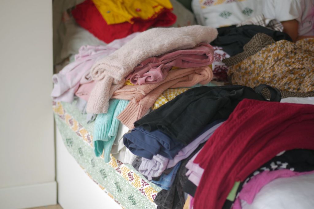 declutter de toamna printre haine asezate in gramada pe un pat
