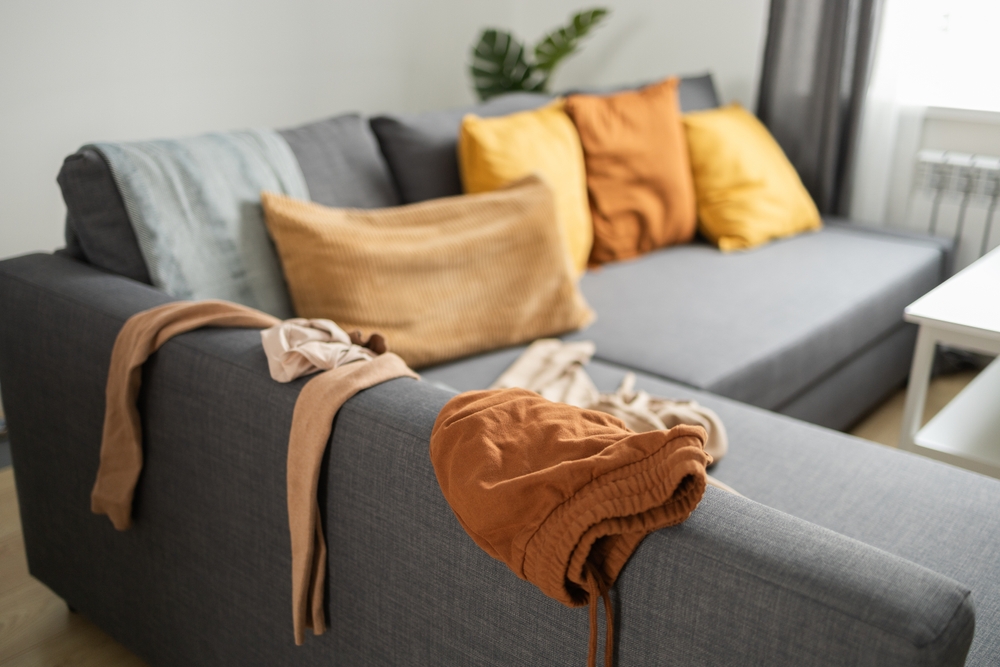 declutter living canapea gri cu haine asezate pe spatar