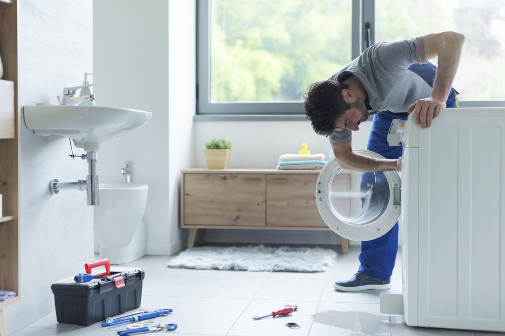 instalator verifică mașina de spălat haine