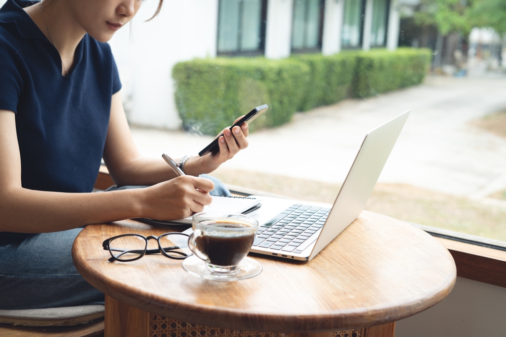 punct de lucru acasă munca de acasa femeie care muncește la laptop si telefon si are pe masa cafea si ochelari