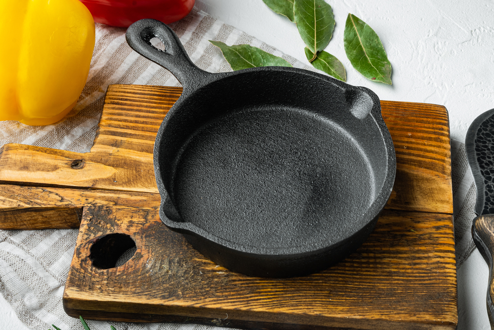 tigaie de fonta pe blat de lemn lângă legume
