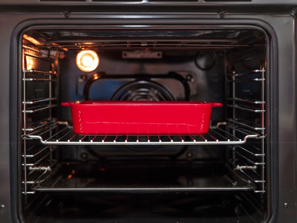 vas roșu din fontă în cuptorul electric cu lumina aprinsă la interior