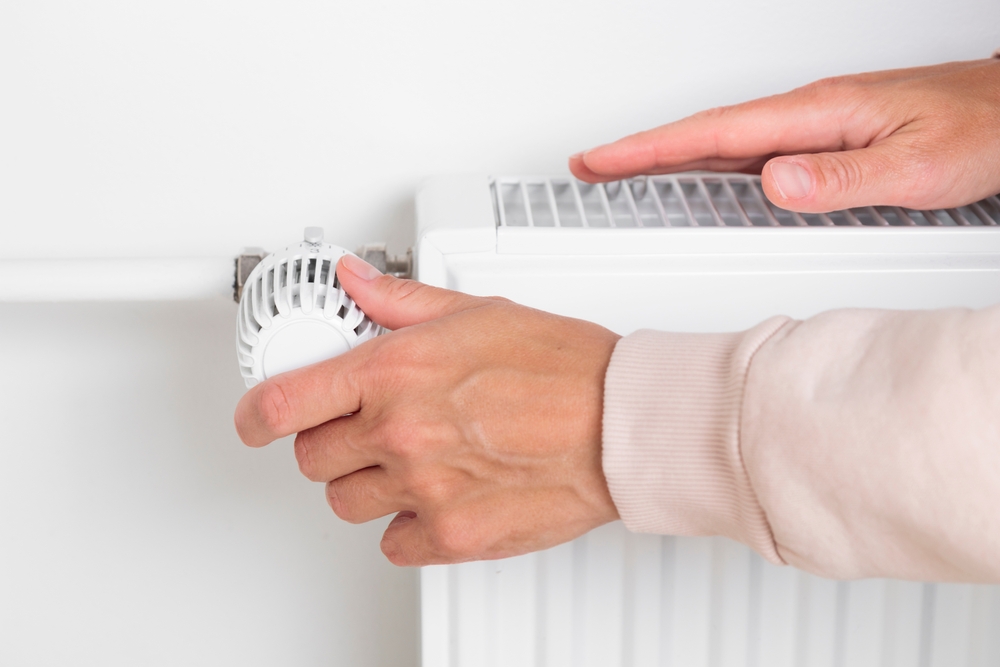 încălzire centrala casa cu calorifer si mana de femeie care îl pornește