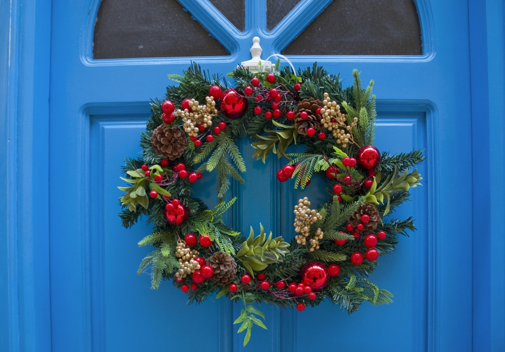 coronita de brad pe usa craciun brad natural cu ornamente rosii pe fundal usa vopsita in albastru