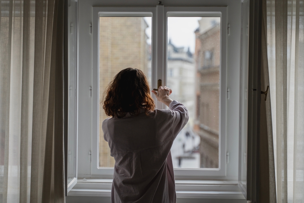 donna che ventila la casa con le finestre aperte