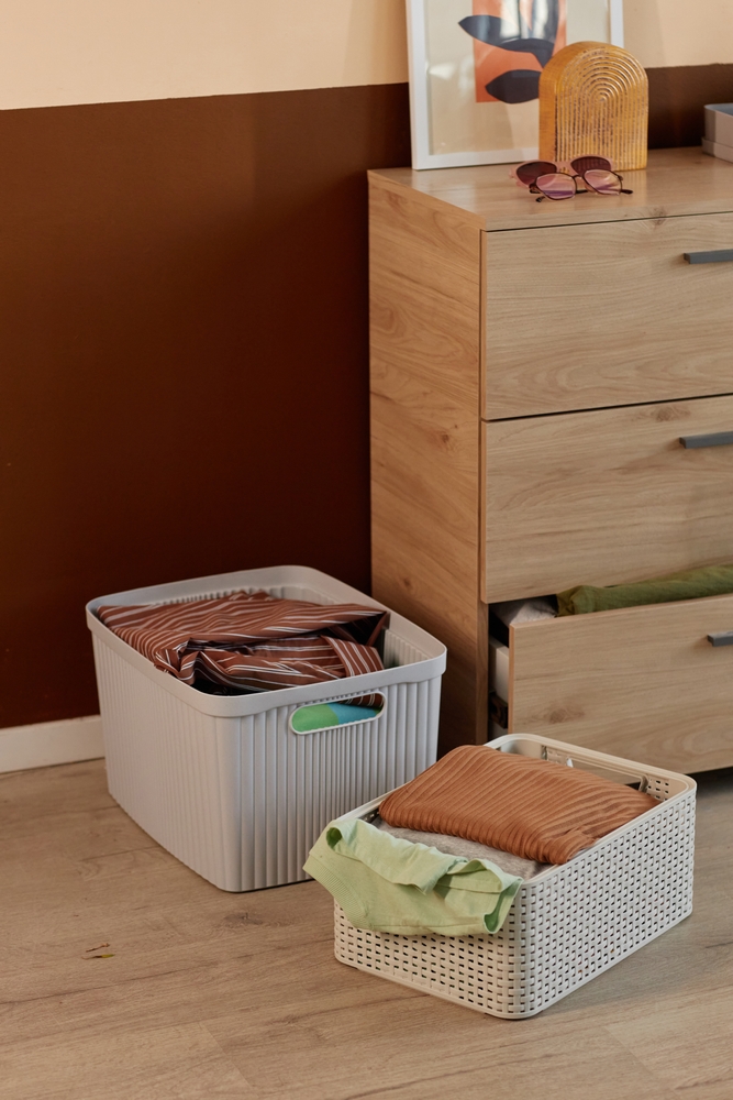 cum scapi de aglomeratia din casa haine in cutii langa un dulap cu sertare intr-o camera cu perete vopsit in maro si parchet din lemn