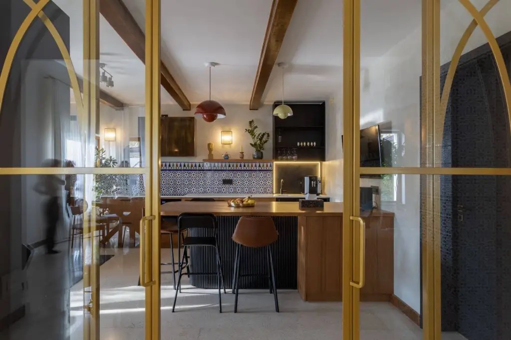 tendinte design interior 2026 neo deco influente africane intr-o amenajare de bucatarie cu insula si pereti glasvand cu structura metalica aurie