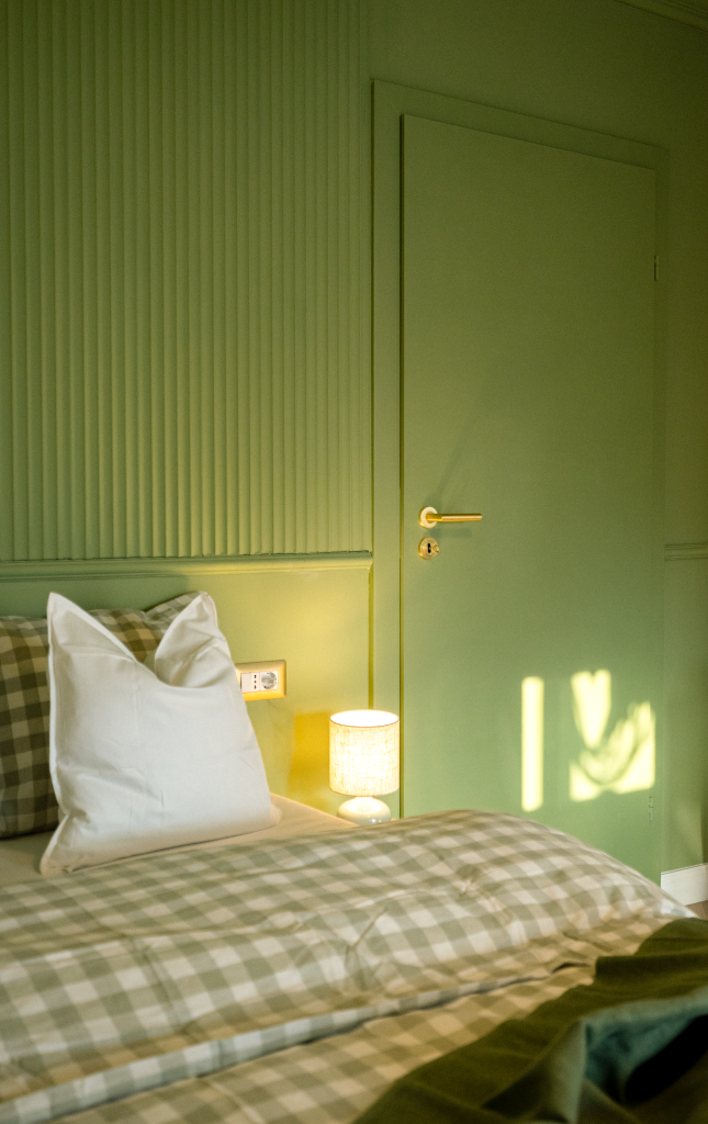 dormitor amenajat in verde cu usa vopsita tot verde si asternuturi alb cu verde