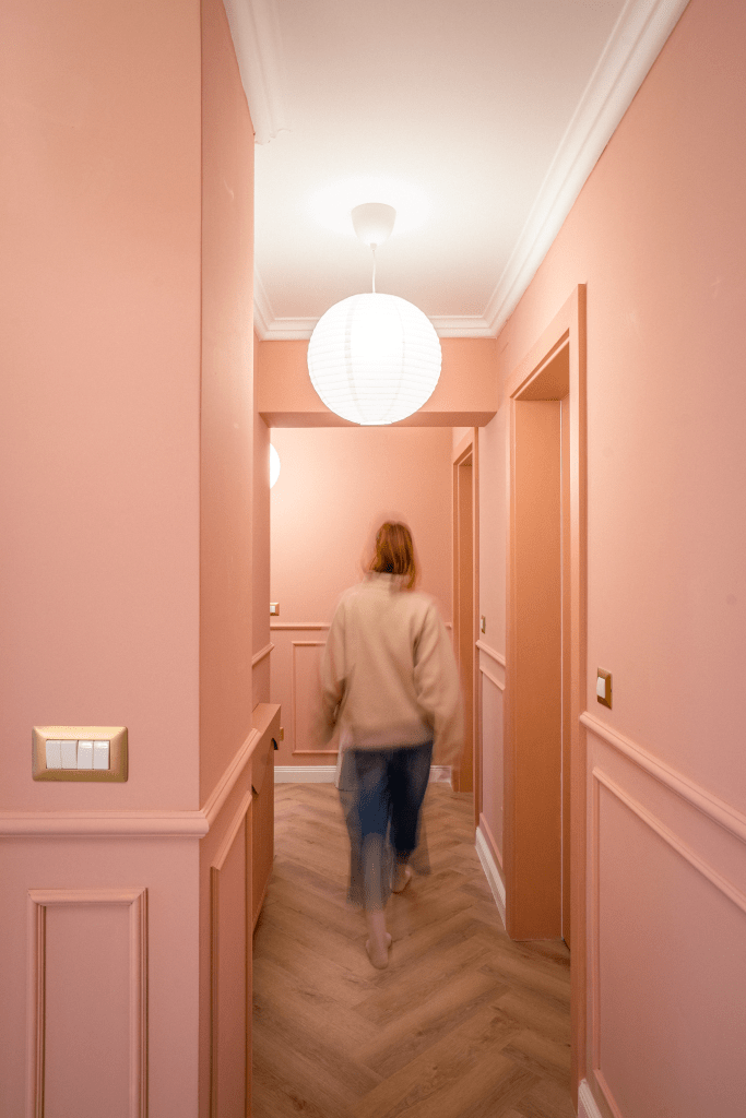 hol intrare in apartament cu pereti vopsiti in roz coral si parchet din lemn