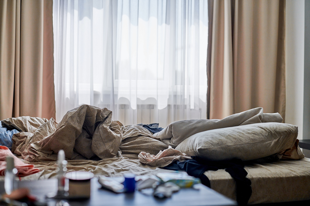 regula de 15 zile decluttering intr-un dormitor aglomerat cu multe cearsafuri pe pat