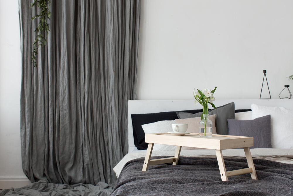 truc de design cu draperii gri uni lungi pana in pamant pe peretele cu patul intr-un dormitor cu pereti albi