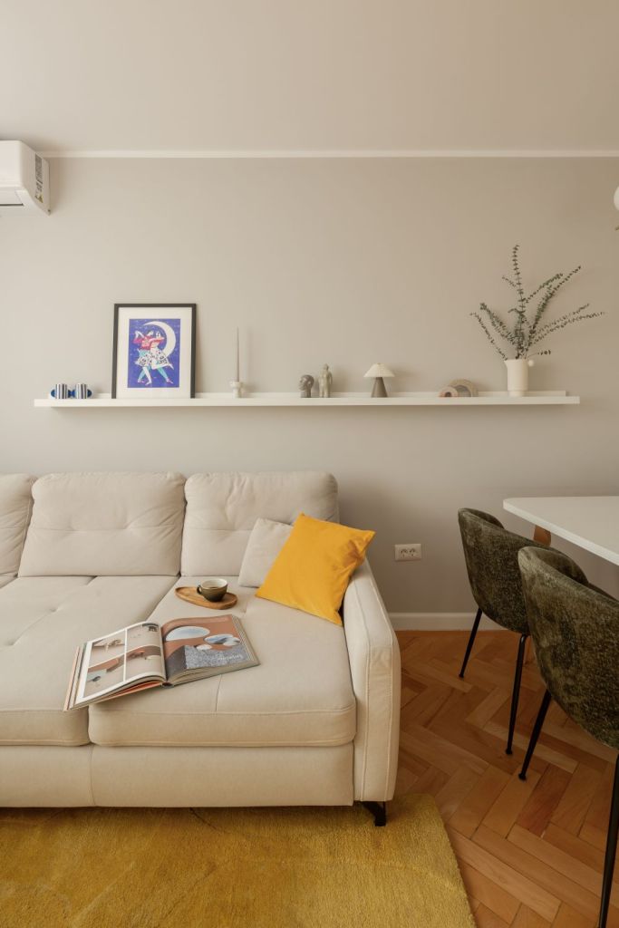 amenajare living stil scandinav cu influente mid century modern si japandi, cu parchet din lemn masiv in format herringbone si coltar alb pereti gri deschis si comoda din lemn in nuanta calda