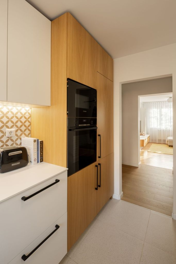 amenajare bucatarie cu alb si furnir de stejar corpuri de depozitare in forma de L si masa cu doua scaune