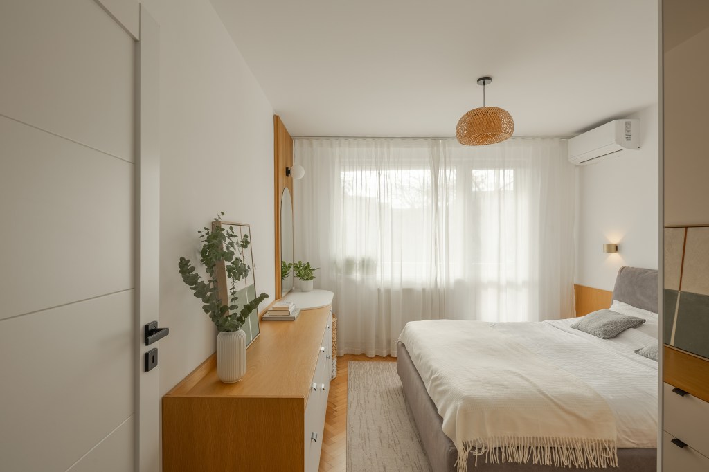 amenajare dormitor in stil scandinav cu pereti albi si mobilier din furnir de stejar pat gri si corp de iluminat din ratan