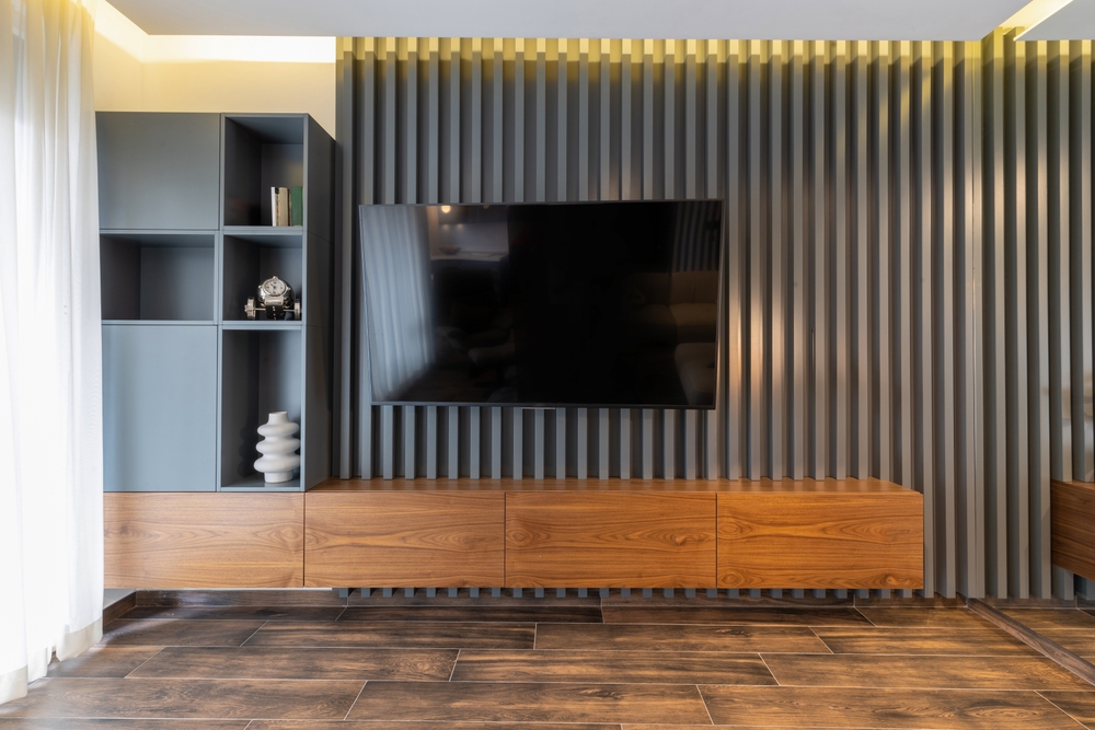 interior living amenajat cu riflaje de lemn vopsite gri pe peretele cu televizorul si comoda media