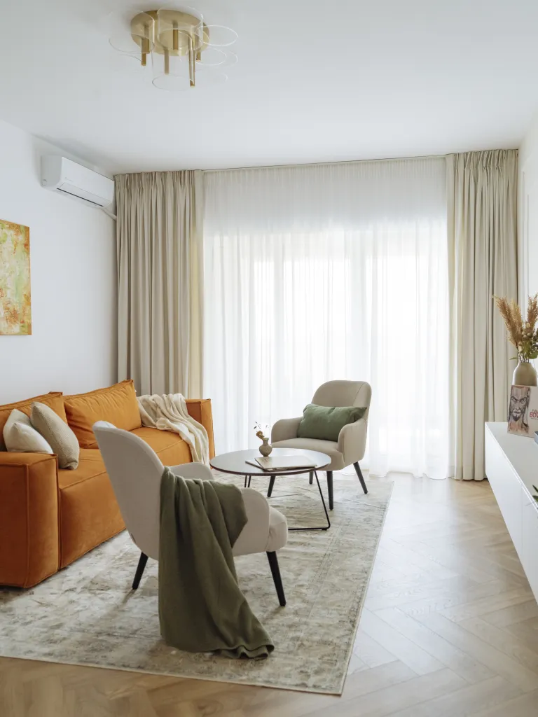 amenajare midimalism pereti culori neutre canapea oranj textile verzi olive pe fotolii si mobilier de depozitare cu linii minimaliste