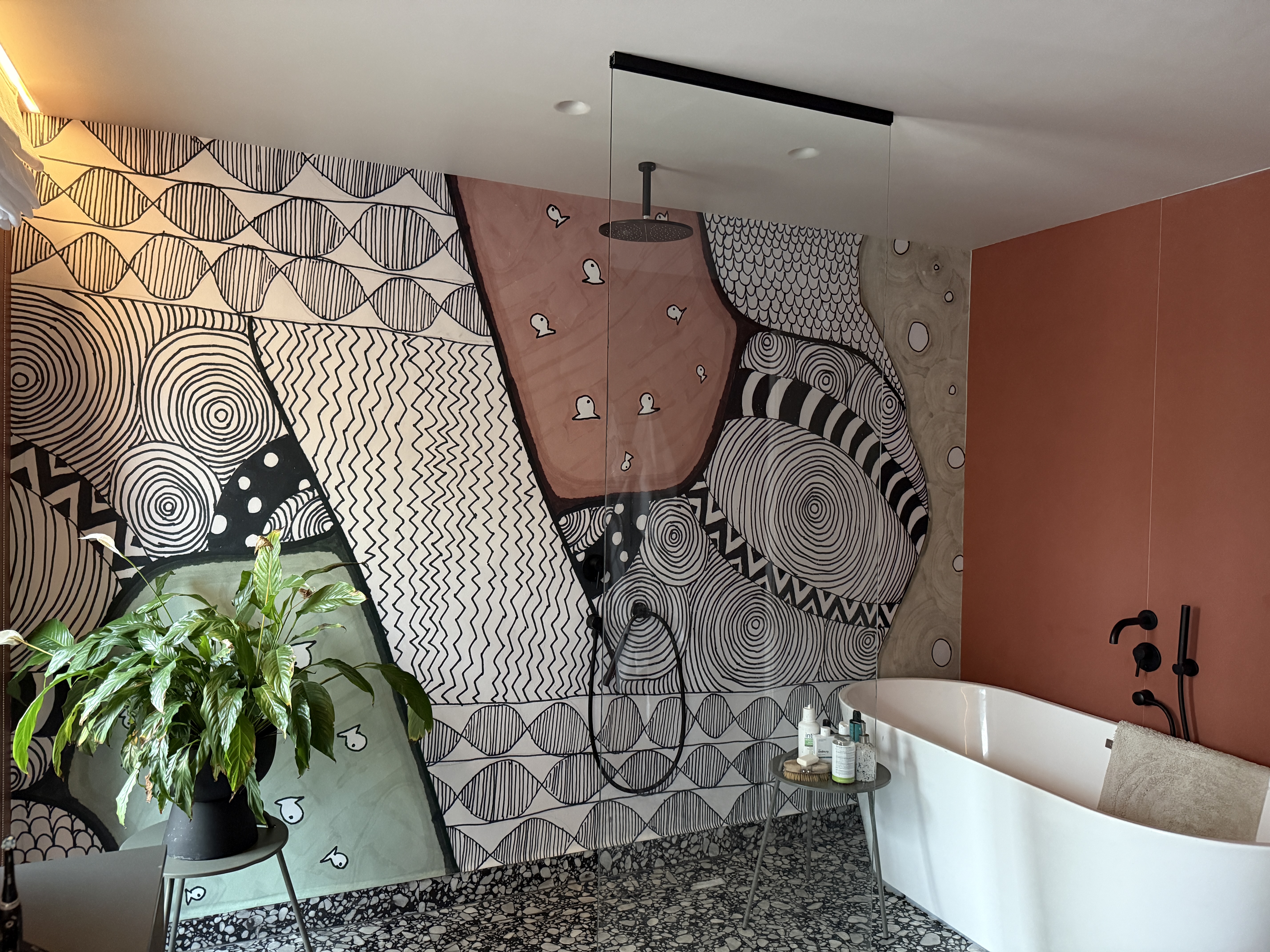 tapet design interior baie moderna cu perete caramiziu planta verde si cada freestanding