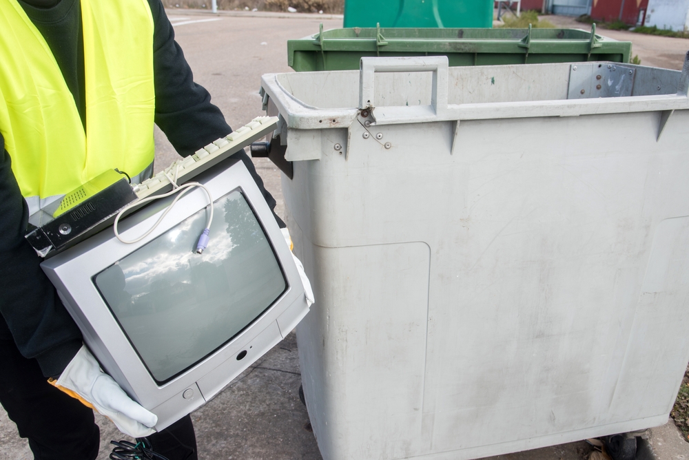 televizor vechi dus la reciclat de către muncitor aflat lângă container dedicat electronicelor uzate