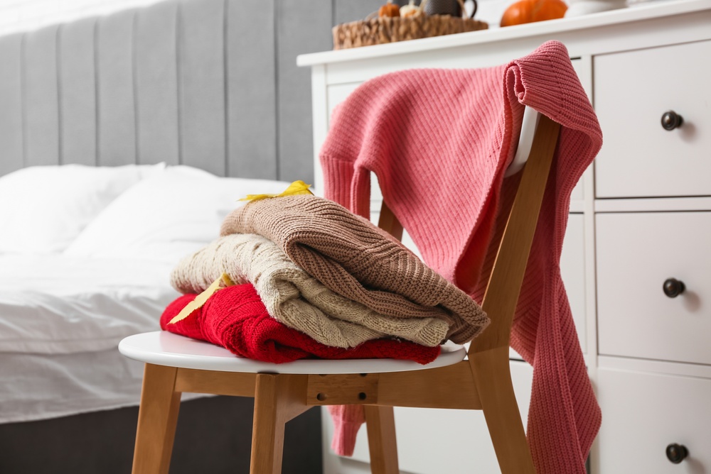 pulovere pe scaunul cu haine intr-un dormitor minimalist