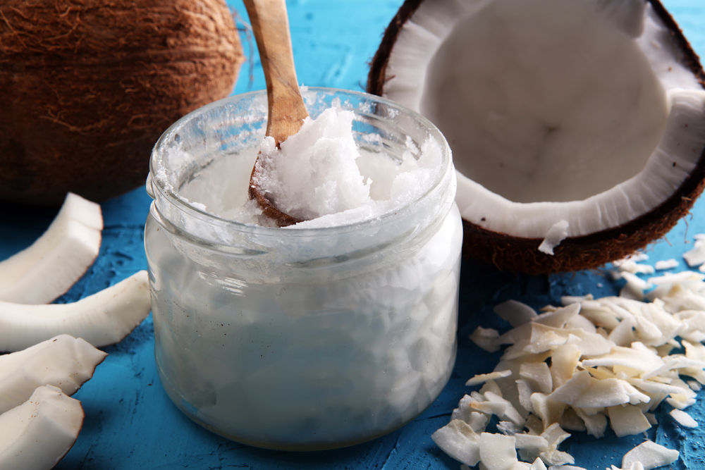 ulei de cocos in pahar alături de nuca de cocos