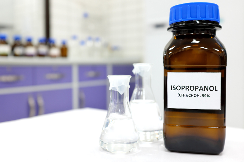Alcool izopropilic la ce se folosește: O sticla închisă la culoare cu alcool izopropilic, cu etichetă albă și capac albastru.