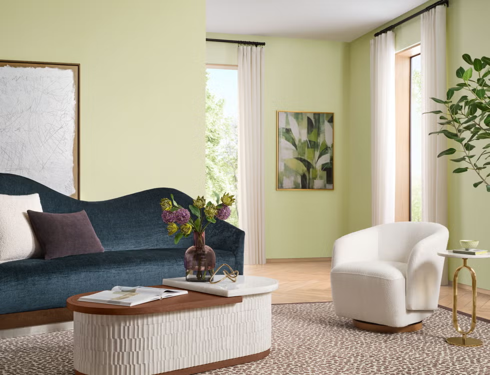 culorile anului 2027 nuanta celery sherwin williams aplicata pe peretii unui living cu canapea albastru bleumarin fotoliu alb si masuta de cafea alba cu blat din lemn natur